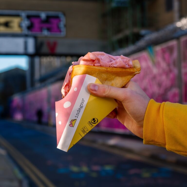 An crescentina sandwich in a hand held over a urband landscape background with graffiti on the walls